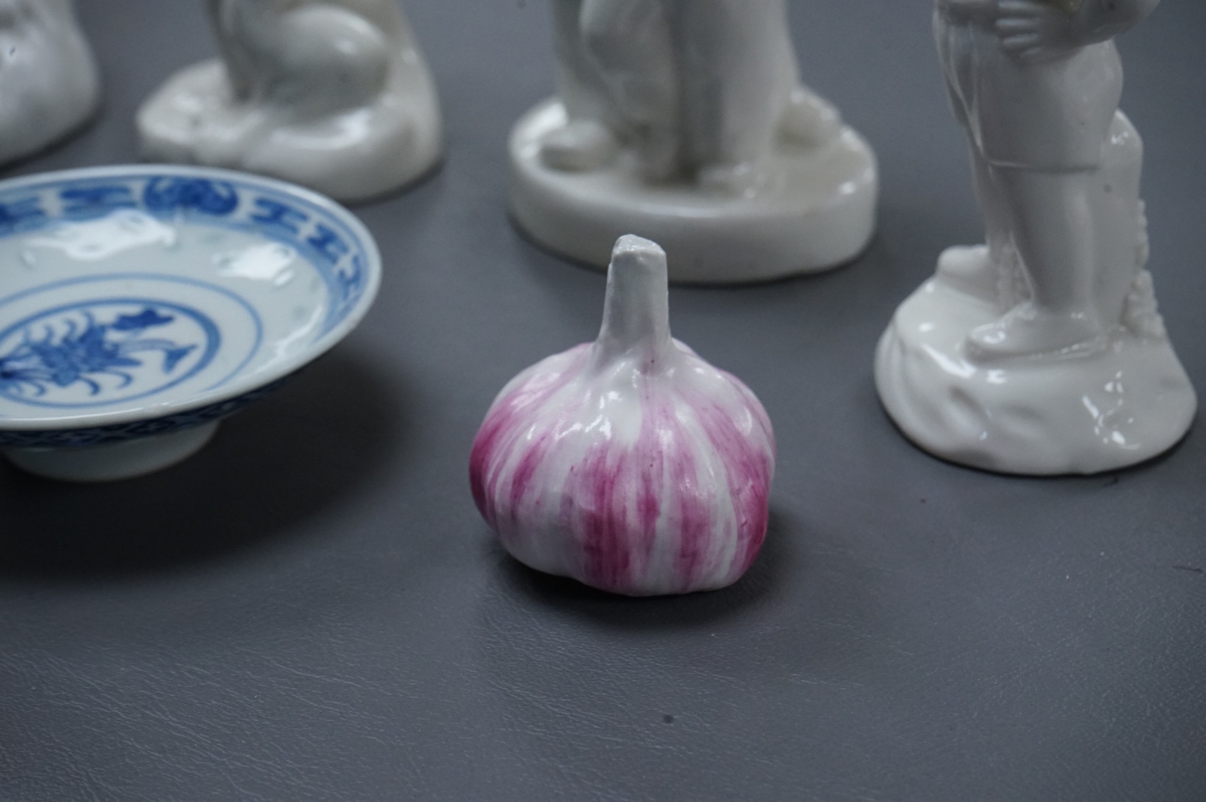 Four Chinese blanc de chine figures and two blue and white dishes and a model of a garlic bulb. Tallest figure 17.5cm.